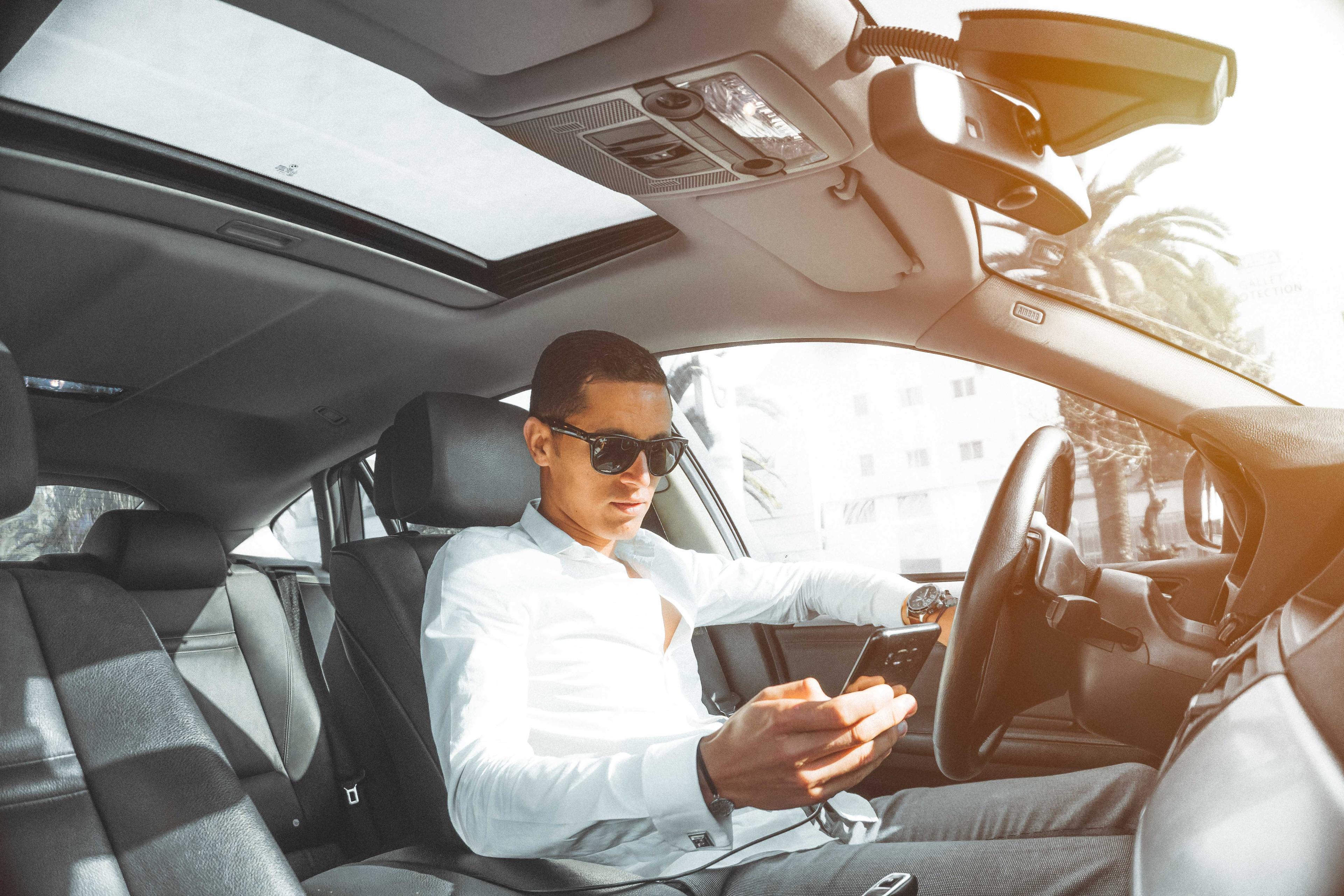 Man holding a phone in driver's seat